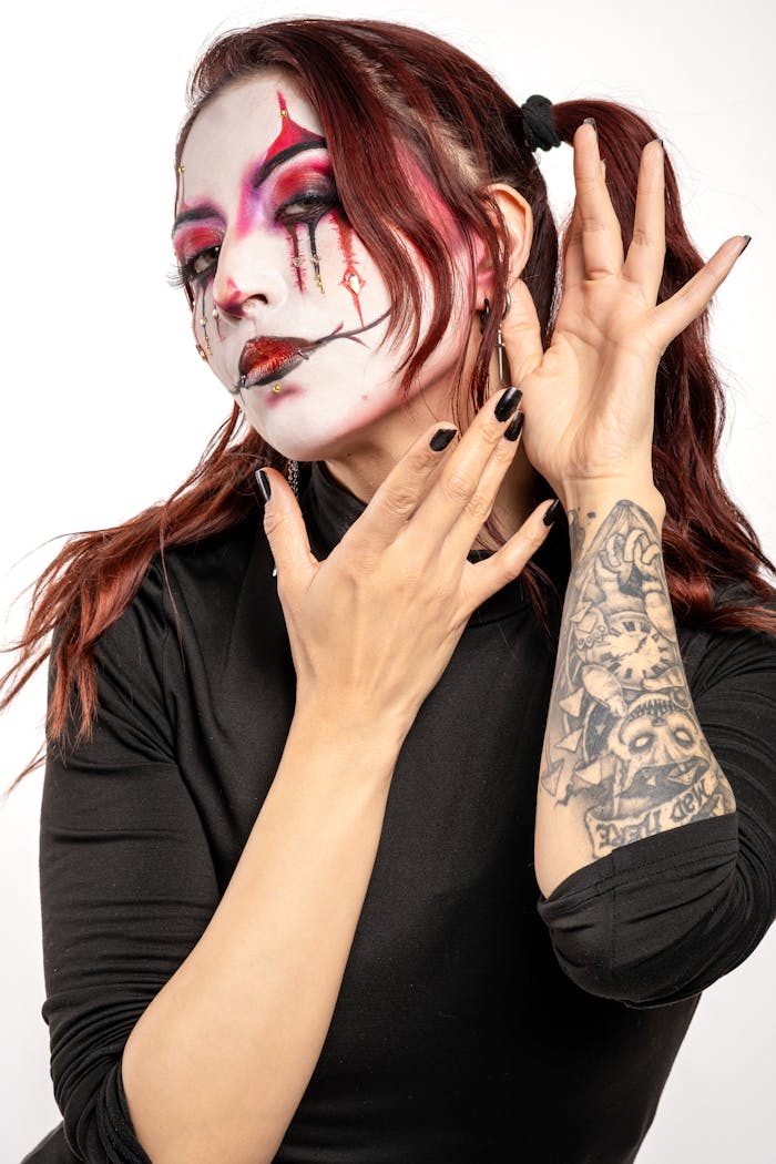 team-02 Striking portrait of a woman in clown makeup with artistic flair and tattooed arm.